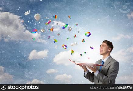 Businessman with book. Young businessman with opened book in hands and diagrams flying from pages
