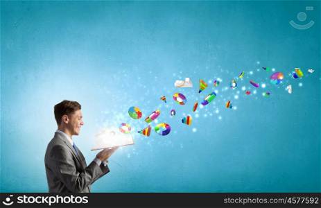 Businessman with book. Young businessman with opened book in hands and infographs flying from pages