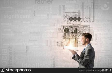 Businessman with book. Young businessman with opened book in hands and infographs on background