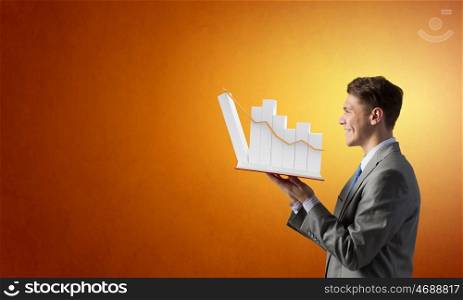 Businessman with book. Young businessman with opened book in hands and infographs on pages