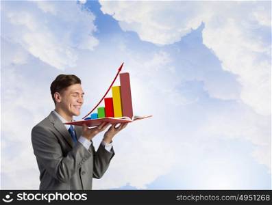 Businessman with book. Young businessman with opened book in hands and infographs on pages