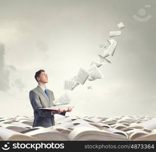 Businessman with book. Young businessman with opened book in hands and pages flying in air