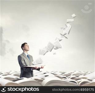 Businessman with book. Young businessman with opened book in hands and pages flying in air