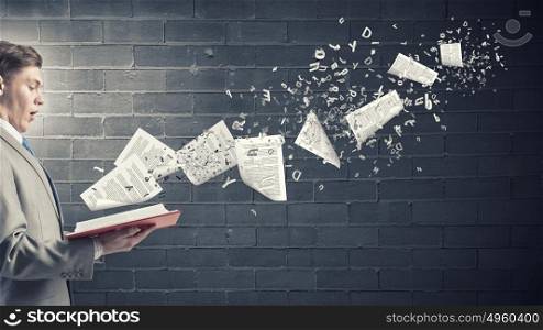 Businessman with book. Young businessman with opened book in hands and pages flying in air