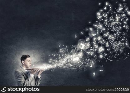 Businessman with book. Young businessman with opened book in hands blowing on pages