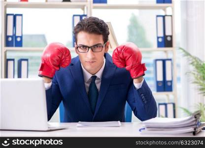 Businessman with boxing gloves angry in office