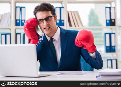 Businessman with boxing gloves angry in office