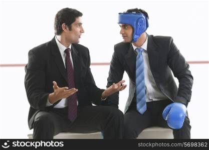 Businessman with boxing gloves listening to his colleague