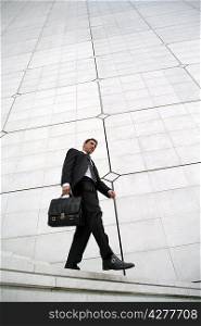 Businessman with briefcase walking down steps