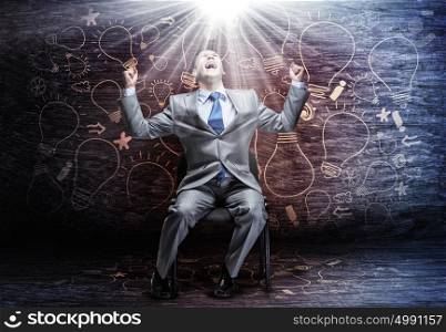 Businessman with briefcase. Young businessman sitting on chair and screaming joyfully