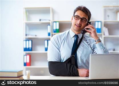 Businessman with broken arm working in office