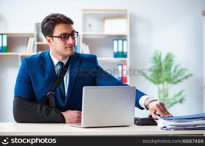 Businessman with broken arm working in office