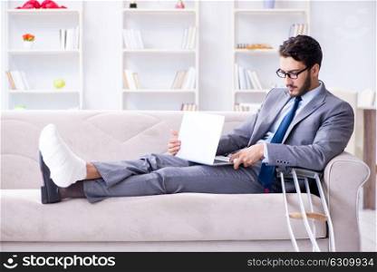 Businessman with crutches and broken leg at home working