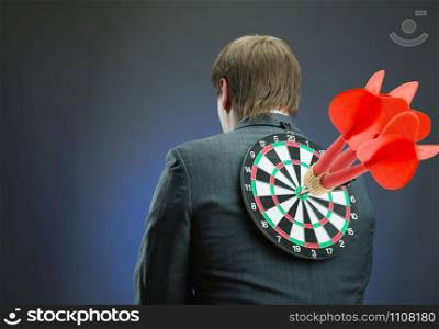 Businessman with darts board on his back with red darts