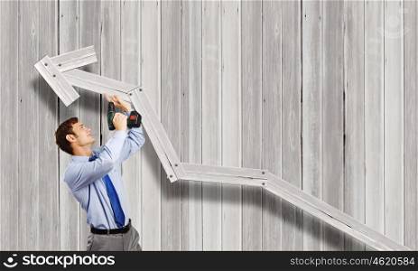 Businessman with drill. Young businessman using drill to fix growing arrow