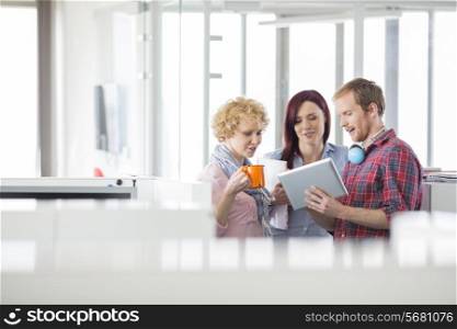 Businessman with female colleagues discussing over tablet PC in office