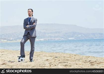 Businessman with football on beach