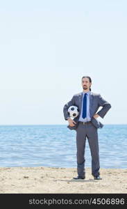 Businessman with football on beach