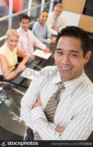 Businessman with four businesspeople at boardroom table in background