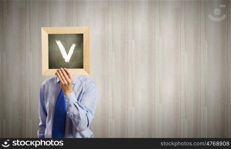 Businessman with frame. Unrecognizable businessman holding wooden frame with tick mark