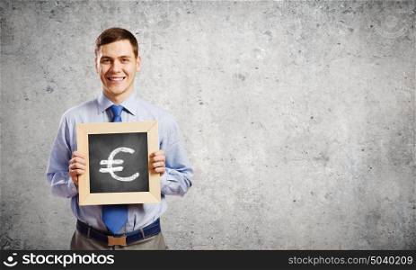 Businessman with frame. Young smiling businessman holding chalkboard with euro sign