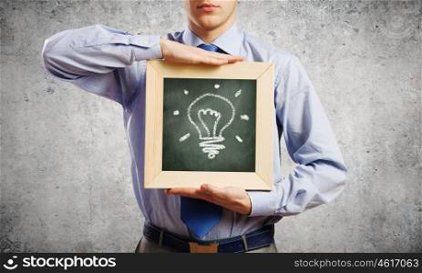 Businessman with frame. Young smiling businessman holding chalkboard with idea sign