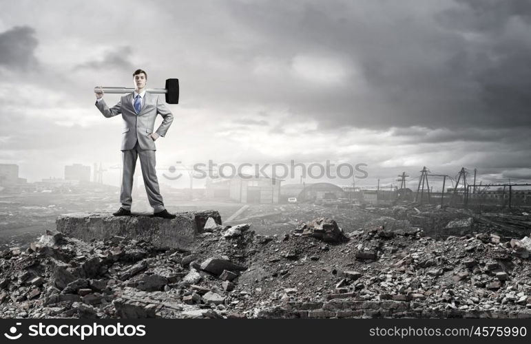 Businessman with hammer. Young determined businessman with big hammer in hands