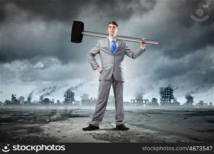 Businessman with hammer. Young determined businessman with big hammer in hands
