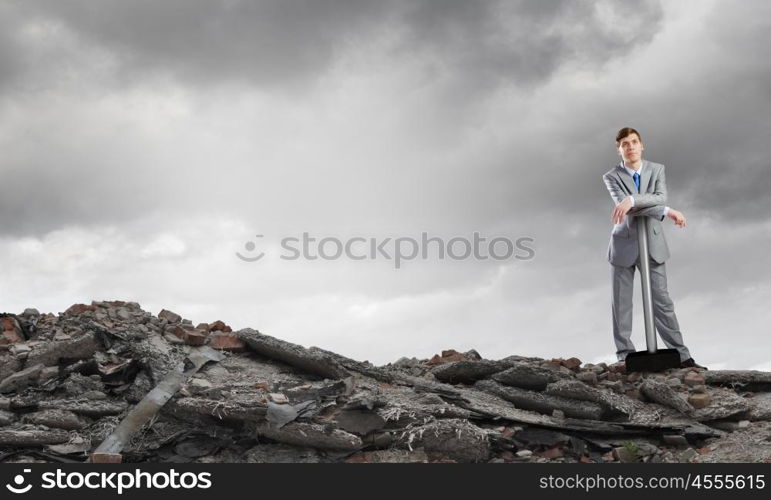 Businessman with hammer. Young determined businessman with big hammer in hands standing on ruins