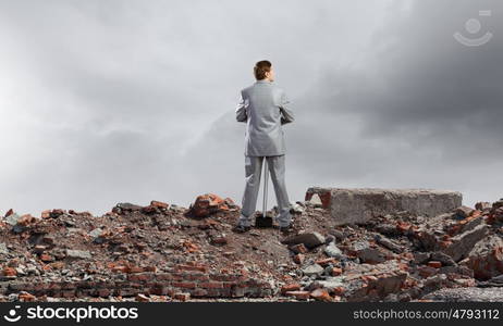 Businessman with hammer. Young determined businessman with big hammer in hands standing on ruins