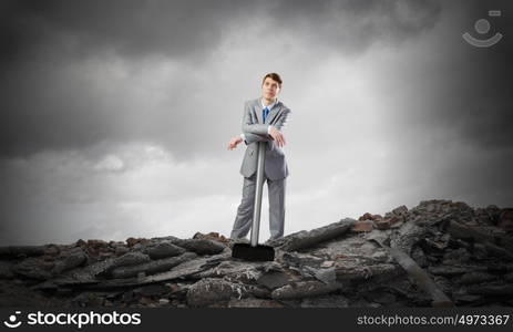 Businessman with hammer. Young determined businessman with big hammer in hands standing on ruins