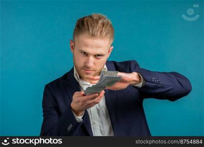 Businessman with happy face scatters money. Man overspend USD currency. Guy is flush with dollars on blue studio background. High quality photo. Businessman with happy face scatters money. Man overspend USD currency. Guy is flush with dollars on blue studio background.