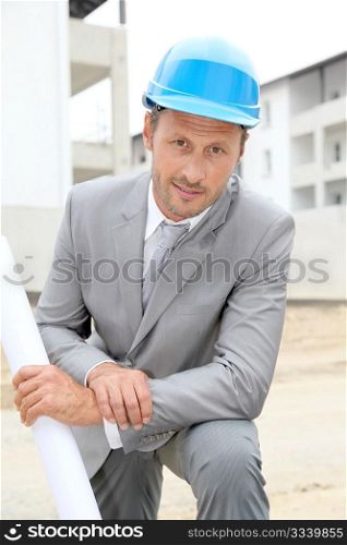 Businessman with helmet checking site under construction