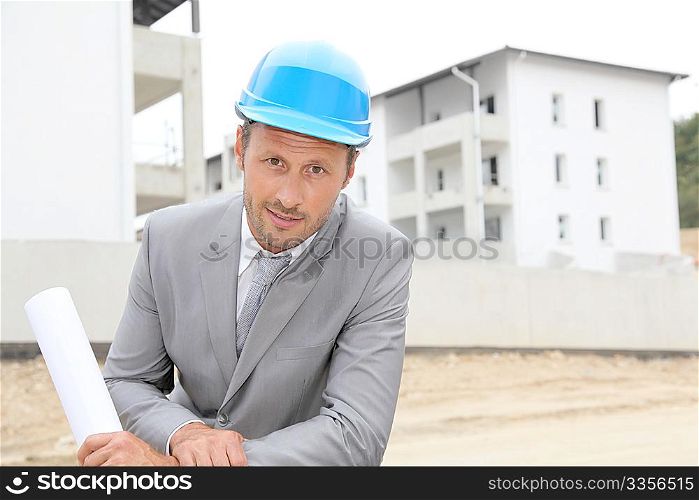 Businessman with helmet checking site under construction
