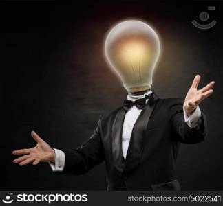 Businessman with lamp head on black background. Welcoming gesture