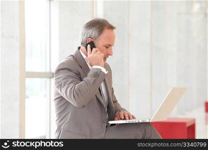 Businessman with laptop computer waiting in hall