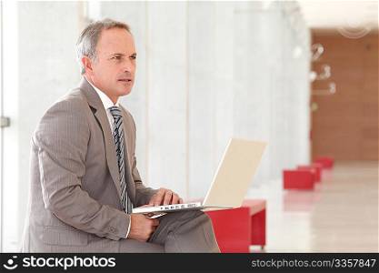 Businessman with laptop computer waiting in hall