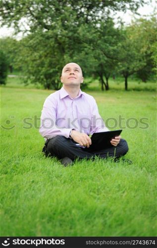 Businessman with laptop on the green grass in the park