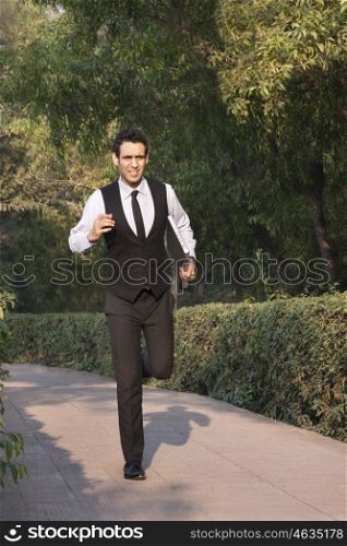Businessman with laptop running in a park , INDIA , DELHI