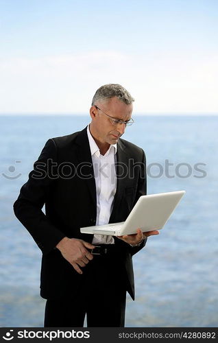 Businessman with laptop stood by lake