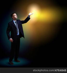 Businessman with light shining. Young successful businessman holding a shining light in his hand as a symbol of success and advancement.