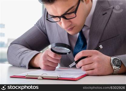 Businessman with magnifying glass studying agreement