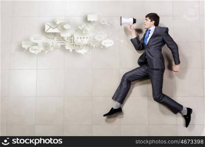 Businessman with megaphone. Funny image of running businessman holding megaphone