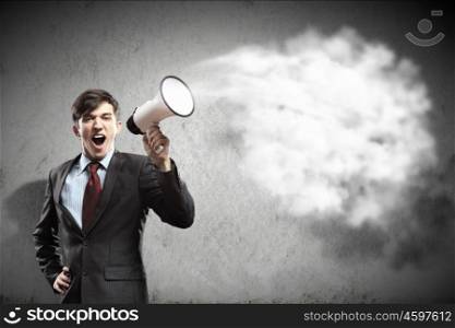 businessman with megaphone. young businessman in black suit screaming into megaphone