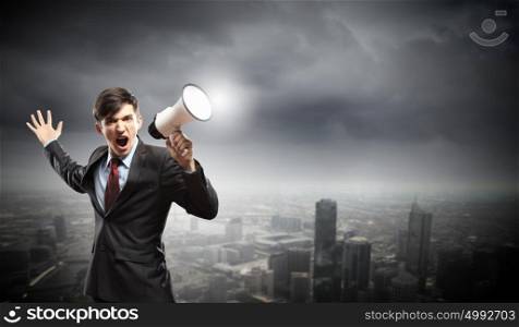 businessman with megaphone. young businessman in black suit screaming into megaphone