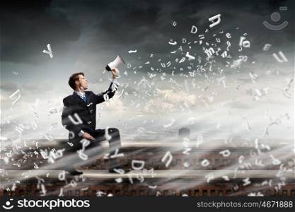 Businessman with megaphone. Young businessman on top of building screaming in megaphone