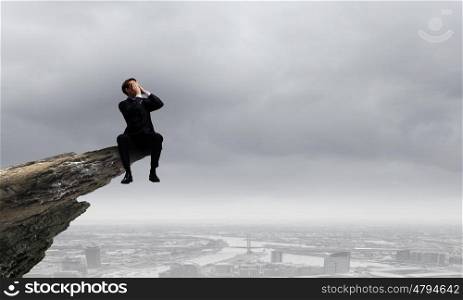 Businessman with megaphone. Young businessman on top of rock screaming in megaphone