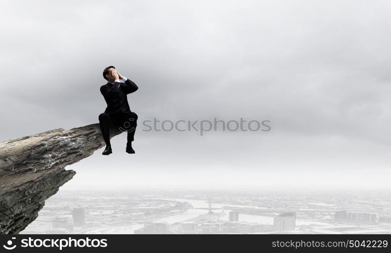 Businessman with megaphone. Young businessman on top of rock screaming in megaphone