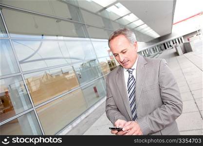 Businessman with mobile phone in front of modern building