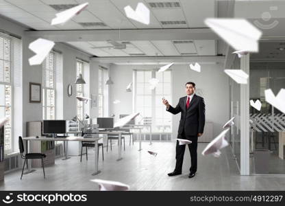 Businessman with mobile phone in hand. Adult businessman in modern office interior using mobile phone